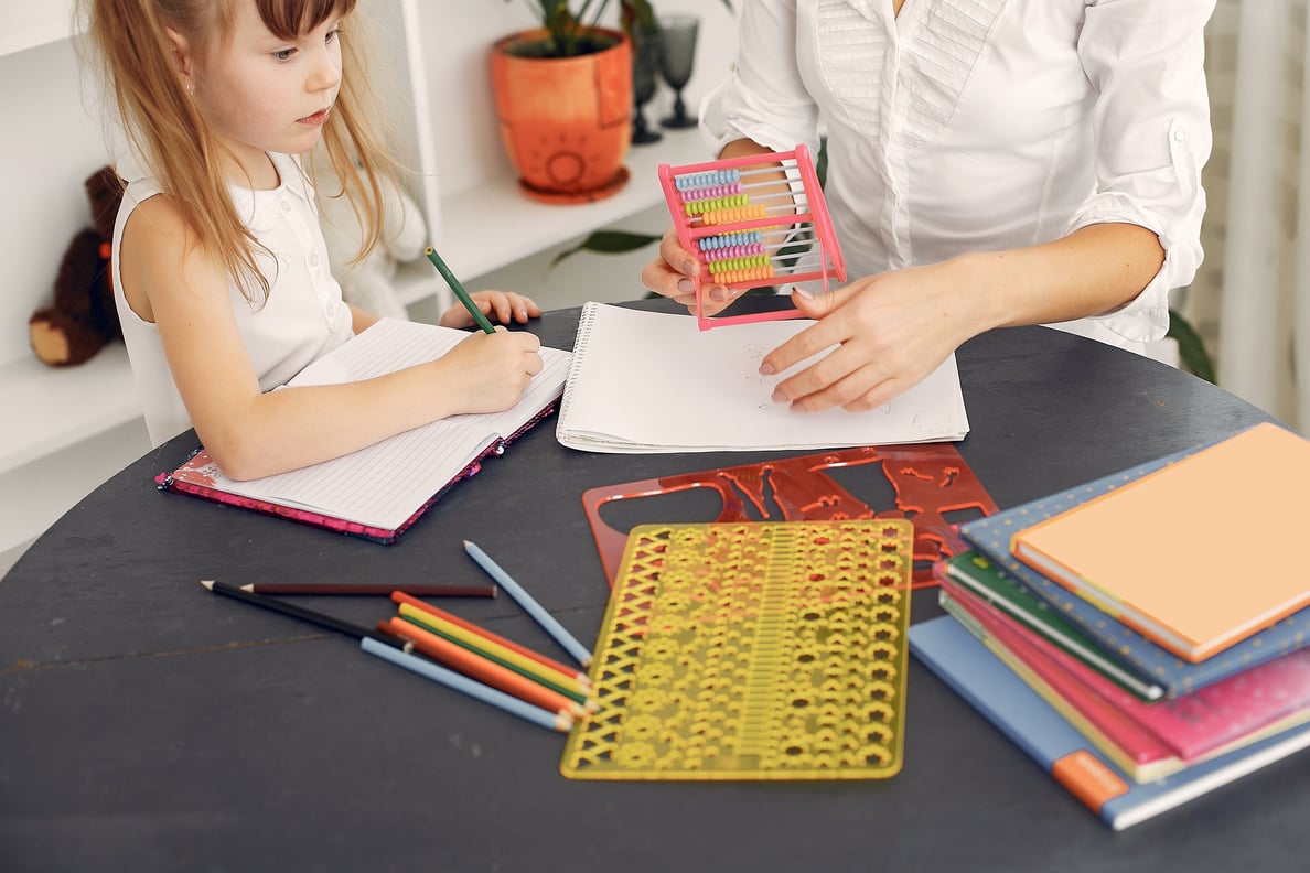 Crop serious schoolchild learning to write and count with help of female tutor